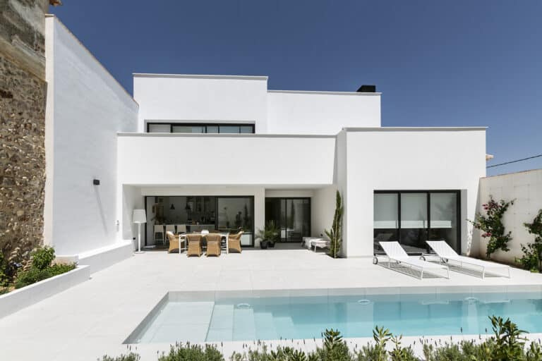 casa blanca estilo mediterranio de dos plantas y moderna con piscina de diseño y dos butacas para tomar el sol, realizada por estudio de arquitecto en Denia