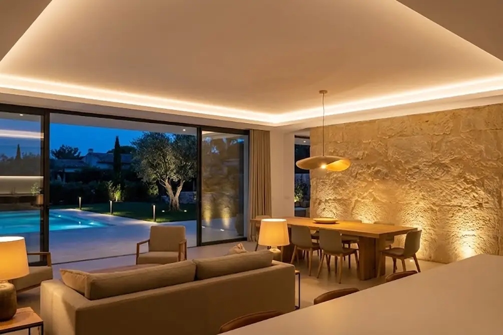 Salón de villa de lujo al anochecer con diseño de iluminación arquitectónica cálida e indirecta.