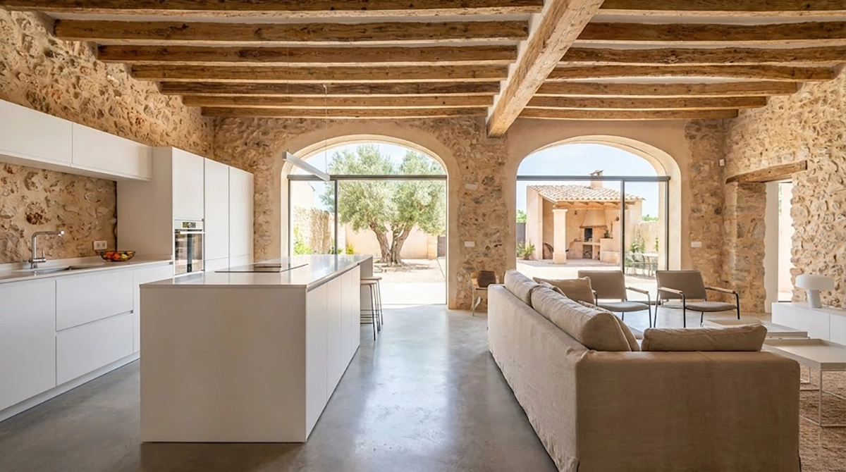 Salón de finca rústica rehabilitada en Benissa, mostrando contraste entre muros de piedra originales y mobiliario moderno.