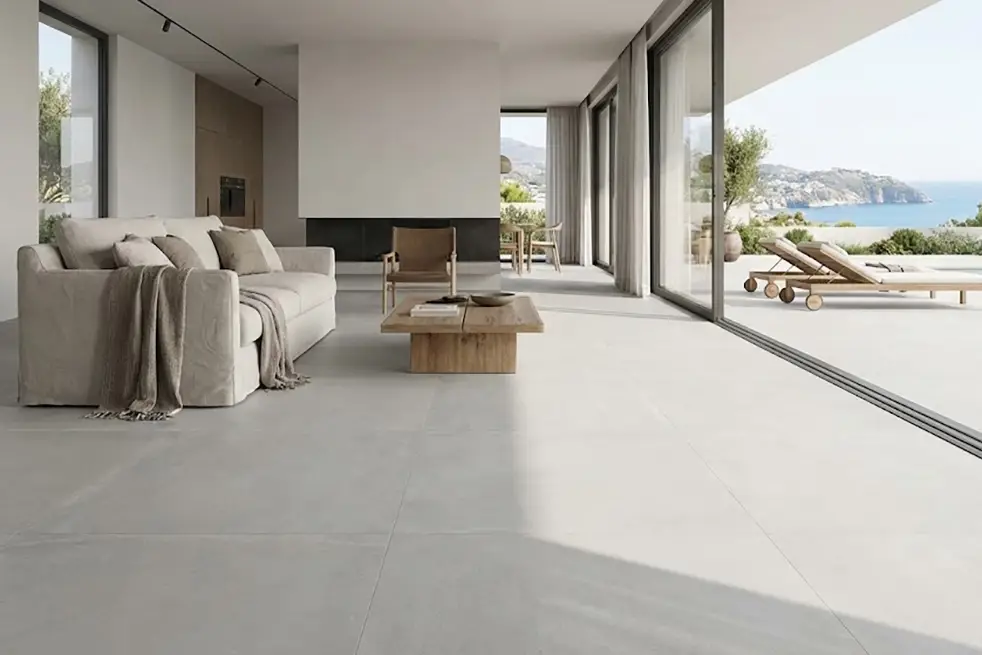 Salón moderno con suelos continuos de gran formato en tono gris, conectando interior y terraza sin juntas visibles.