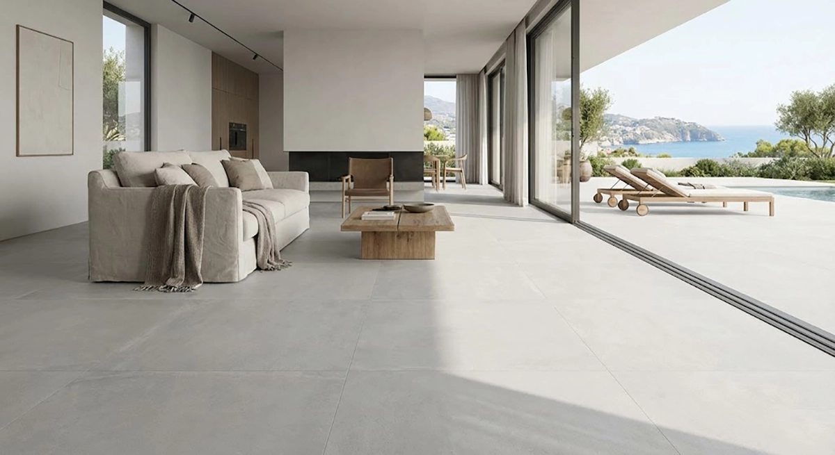 Salón moderno con suelos continuos de gran formato en tono gris, conectando interior y terraza sin juntas visibles.